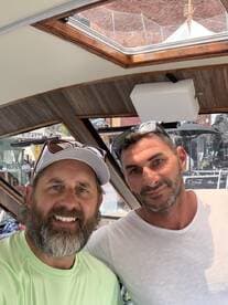 Two men pose for a selfie inside the cabin of a boat, showcasing the stylish interior and inviting atmosphere.