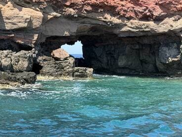 A stunning view of a natural rock formation with an archway, surrounded by clear turquoise waters — a picturesque coastal scene perfect for exploring marine landscapes.