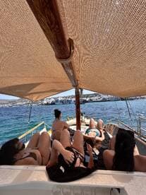 A group of friends relaxes on the deck of a boat, enjoying the sun and beautiful views — perfect for a day of leisure on the water.