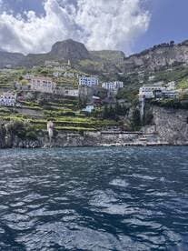 A stunning view of the Amalfi Coast, showcasing picturesque cliffside homes and lush greenery against a dramatic mountainous backdrop — a perfect destination for boat tours and scenic cruises.
