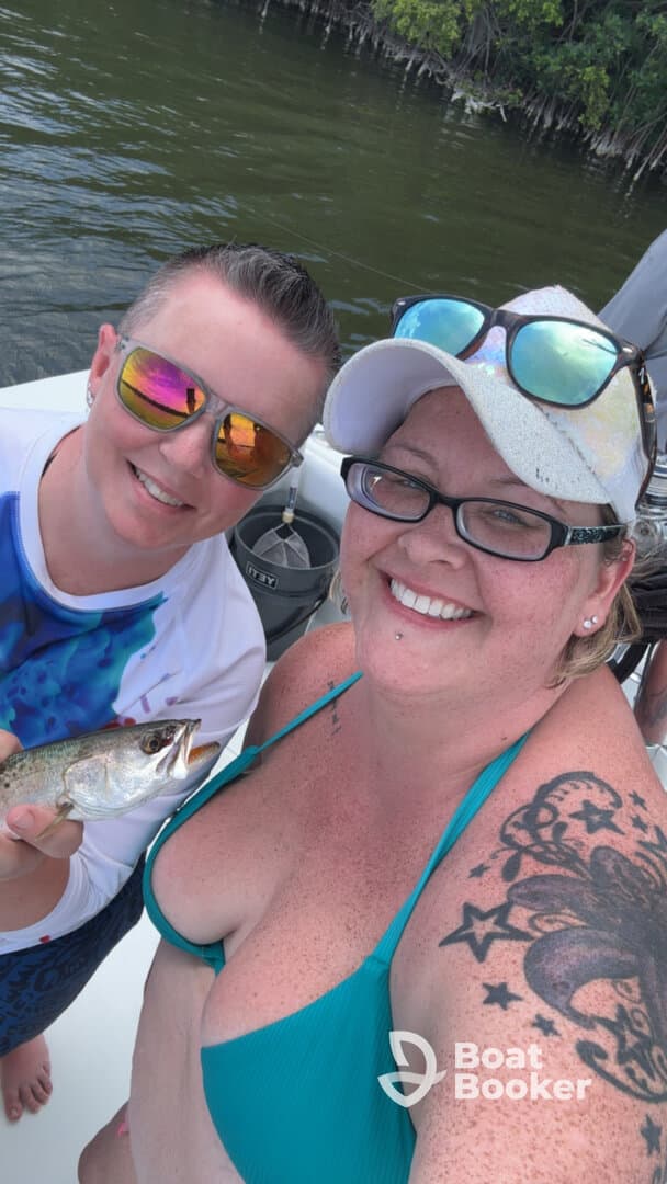 Two friends proudly display their catch while enjoying a fishing trip on the water, capturing a joyful moment of camaraderie and adventure.