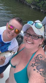 Two friends proudly display their catch while enjoying a fishing trip on the water, capturing a joyful moment of camaraderie and adventure.