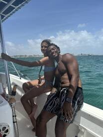 A joyful couple poses on a boat, enjoying a sunny day on the ocean — perfect for romantic getaways or fun adventures at sea.