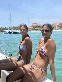 Two young women enjoy a sunny day on a boat, showcasing a fun beach vibe perfect for summer adventures.