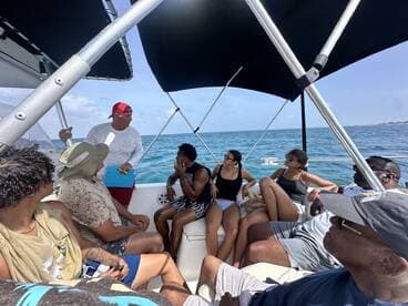 A lively group enjoys a boat tour, engaging with the captain while taking in the beautiful ocean views — perfect for memorable adventures on the water.