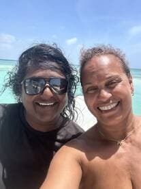 Two friends enjoy a sunny day at the beach, capturing a joyful moment together against a stunning turquoise backdrop — perfect for memorable outings and celebrations.