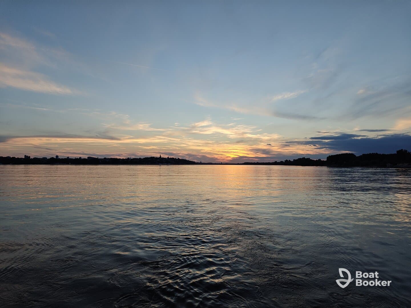 A stunning sunset over calm waters, showcasing the serene beauty of the coastline — perfect for peaceful evening boat rides.