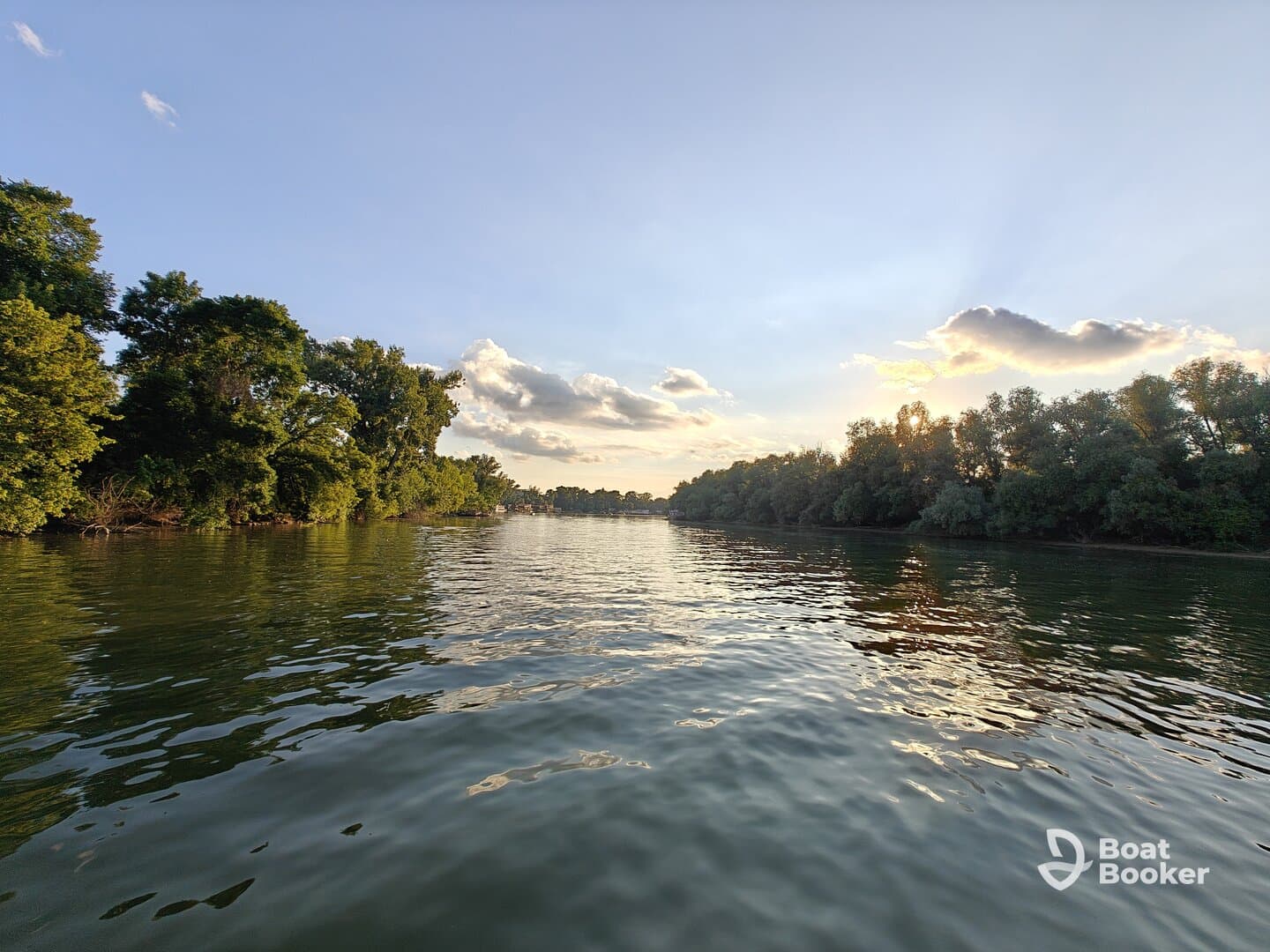 A serene view of the river at sunset, framed by lush greenery along the shoreline — perfect for nature lovers and peaceful boating experiences.