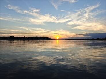 A stunning sunset reflects on calm waters, creating a picturesque scene perfect for evening boat trips and relaxation.