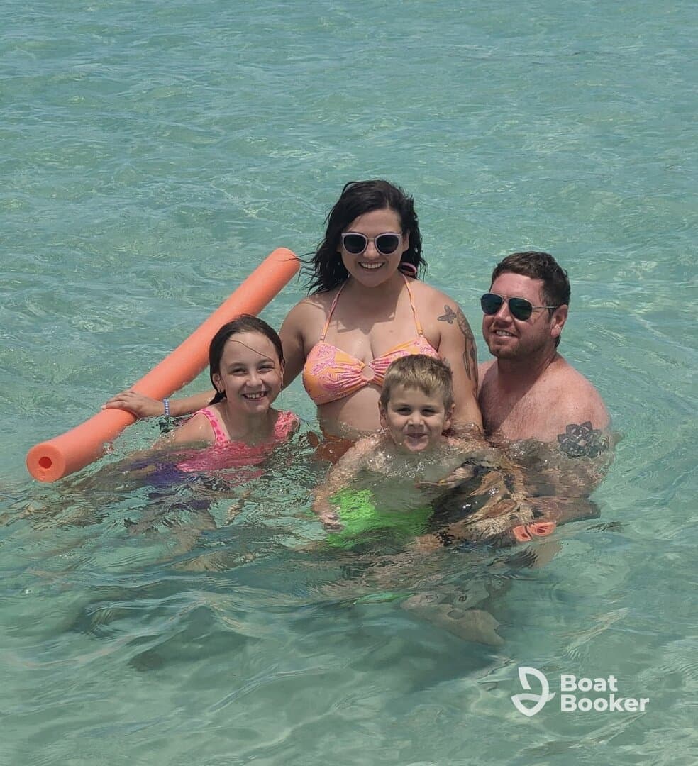 A joyful family enjoys a fun day in the water, with kids playing and swimming in the clear, shallow sea — perfect for memorable beach outings.