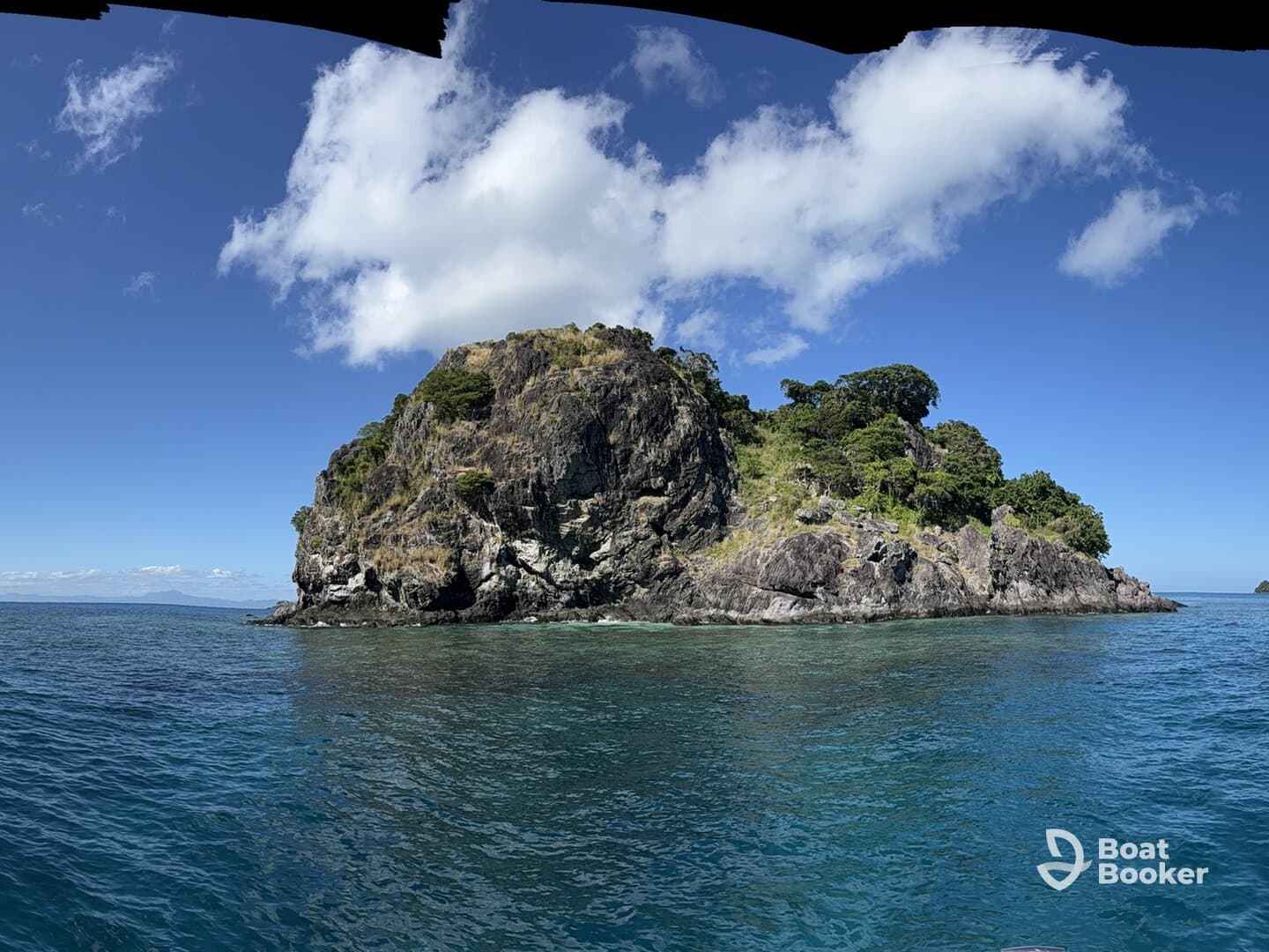 A stunning view of a rocky island surrounded by clear blue waters, showcasing the natural beauty of the coastline — perfect for island hopping adventures.