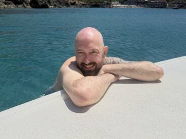A man enjoys a refreshing swim in crystal-clear waters, showcasing a perfect day of relaxation and fun on the water.