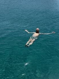 A man enjoys a relaxing float in the crystal-clear waters, capturing the essence of a perfect day on the water.