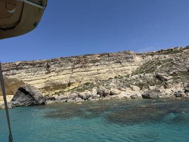 A stunning view of rocky cliffs and clear turquoise waters, showcasing the natural beauty of the coastline — perfect for exploring by boat.