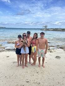 A joyful group of friends poses on the beach, showcasing a fun day in the sun with a dog — perfect for family outings and beach adventures.
