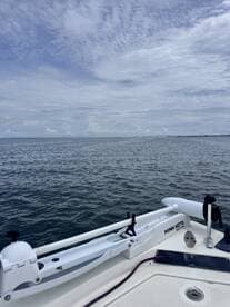 A close-up view of the bow of a boat with a Minn Kota motor, showcasing the calm waters and cloudy sky — perfect for a day of fishing or leisure on the water.