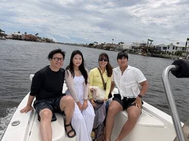 A cheerful group enjoys a boat ride together, capturing a memorable moment with their dog on a scenic waterway.