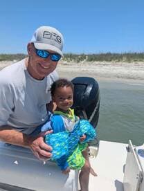 A joyful moment captured on a boat with a child and adult, both wearing life jackets, showcasing a fun family outing on the water.
