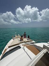 A group enjoys a relaxing day on a boat, surrounded by stunning turquoise waters and a beautiful sky — perfect for a memorable outing on the water.