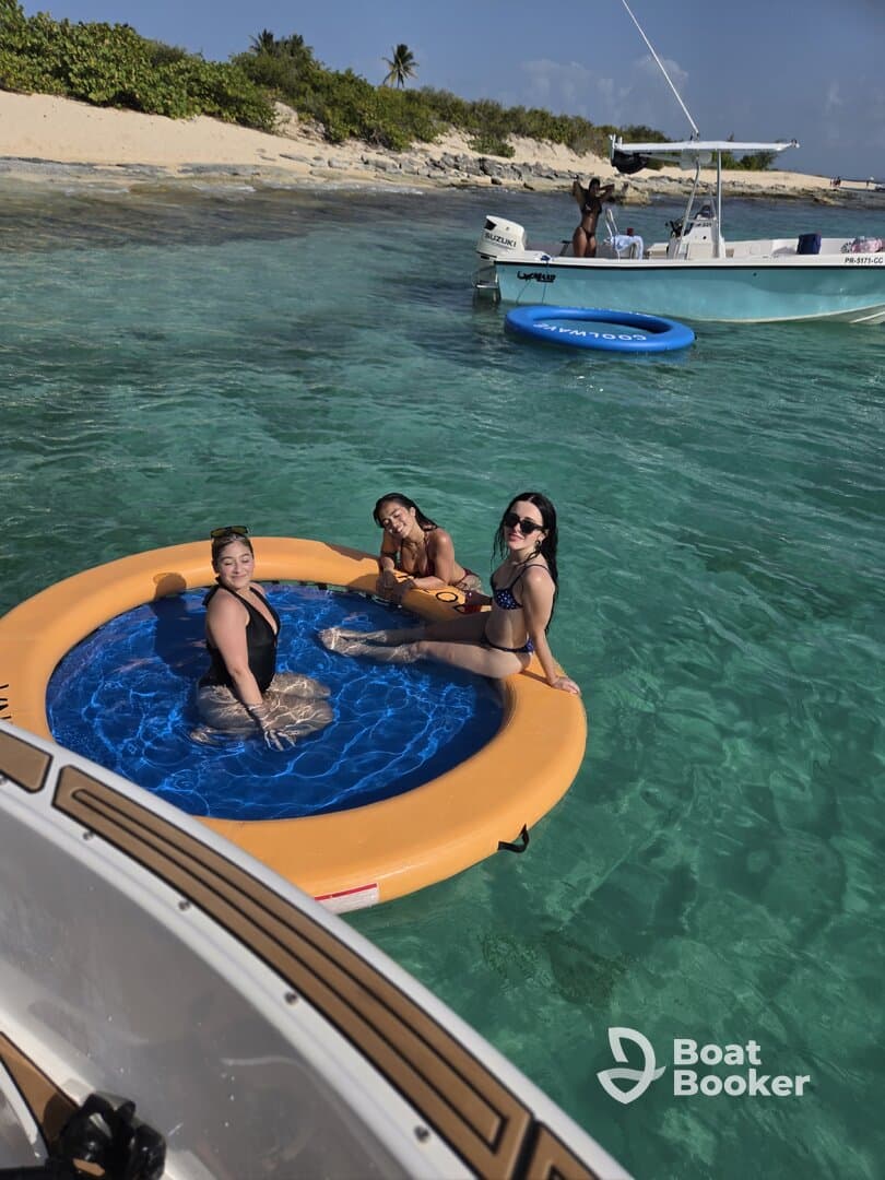 A group of friends enjoys a sunny day on a floating mat in crystal-clear waters, perfect for relaxation and fun under the sun.