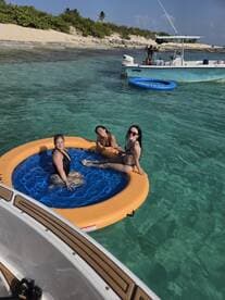 A group of friends enjoys a sunny day on a floating mat in crystal-clear waters, perfect for relaxation and fun under the sun.