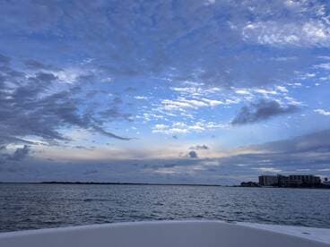 A serene view from the bow of a boat, showcasing a beautiful sky and calm waters, perfect for a peaceful day on the water.
