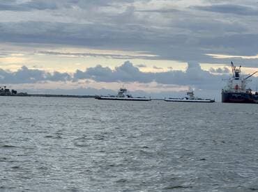 A scenic view of multiple vessels navigating the water, showcasing the maritime activity in the harbor under a cloudy sky.