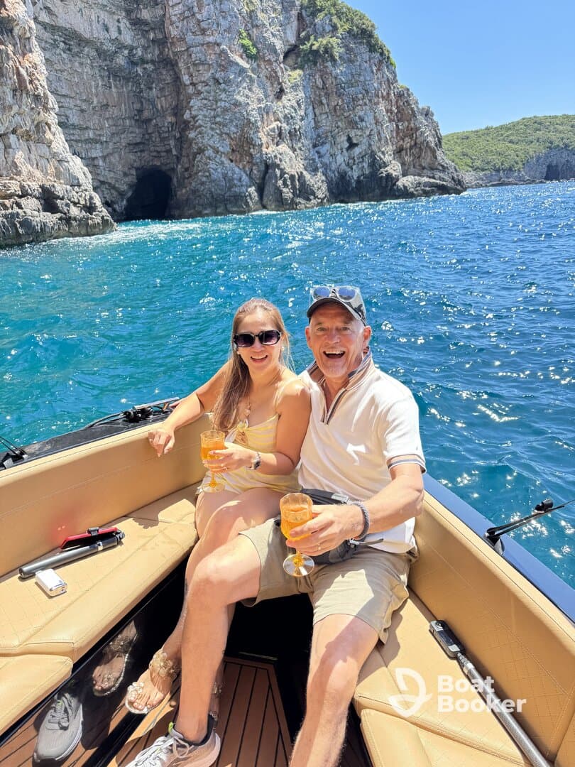 A joyful couple enjoys cocktails on a boat, surrounded by stunning coastal scenery — perfect for romantic getaways or special celebrations on the water.