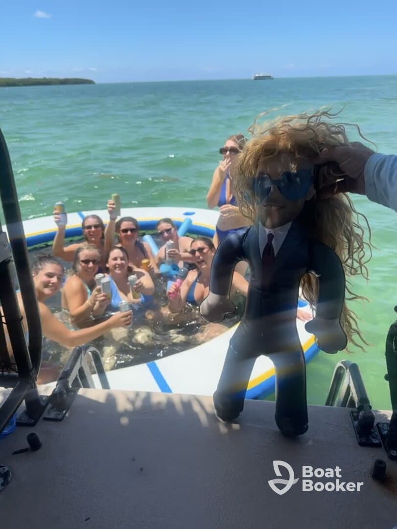 A lively group of friends enjoys a fun day on the water, celebrating with drinks and laughter while swimming around a floating mat.