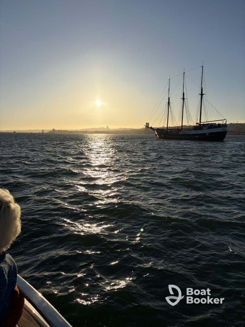 A stunning sunset view over the ocean with a sailing ship in the distance, capturing the essence of a perfect evening on the water.