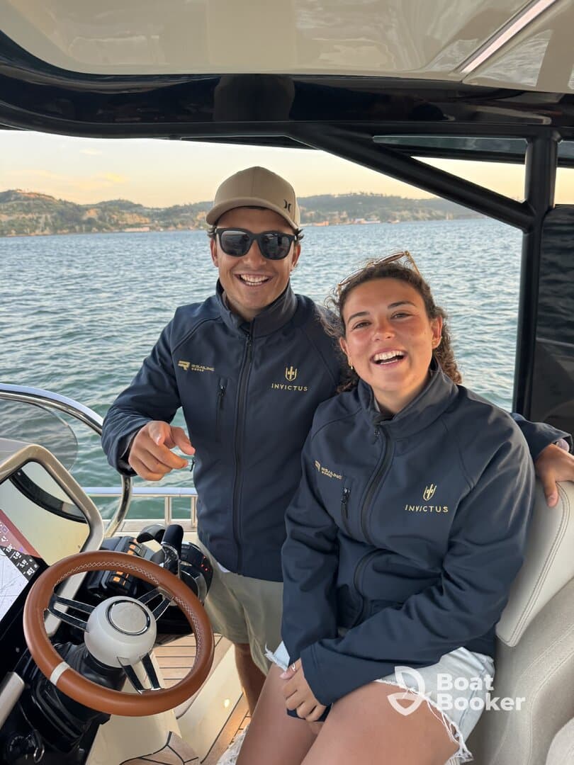 A cheerful duo poses at the helm of a stylish boat, showcasing the modern interior and inviting atmosphere perfect for a day on the water.