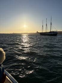 A stunning sunset view over the ocean with a sailing ship in the distance, capturing the essence of a perfect evening on the water.