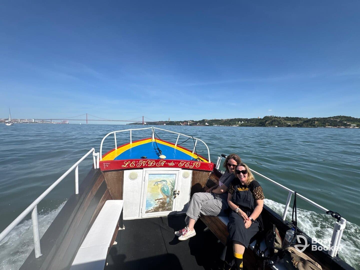 Two friends enjoy a sunny day on a boat in Lisbon, capturing the joy of their aquatic adventure against a scenic backdrop.