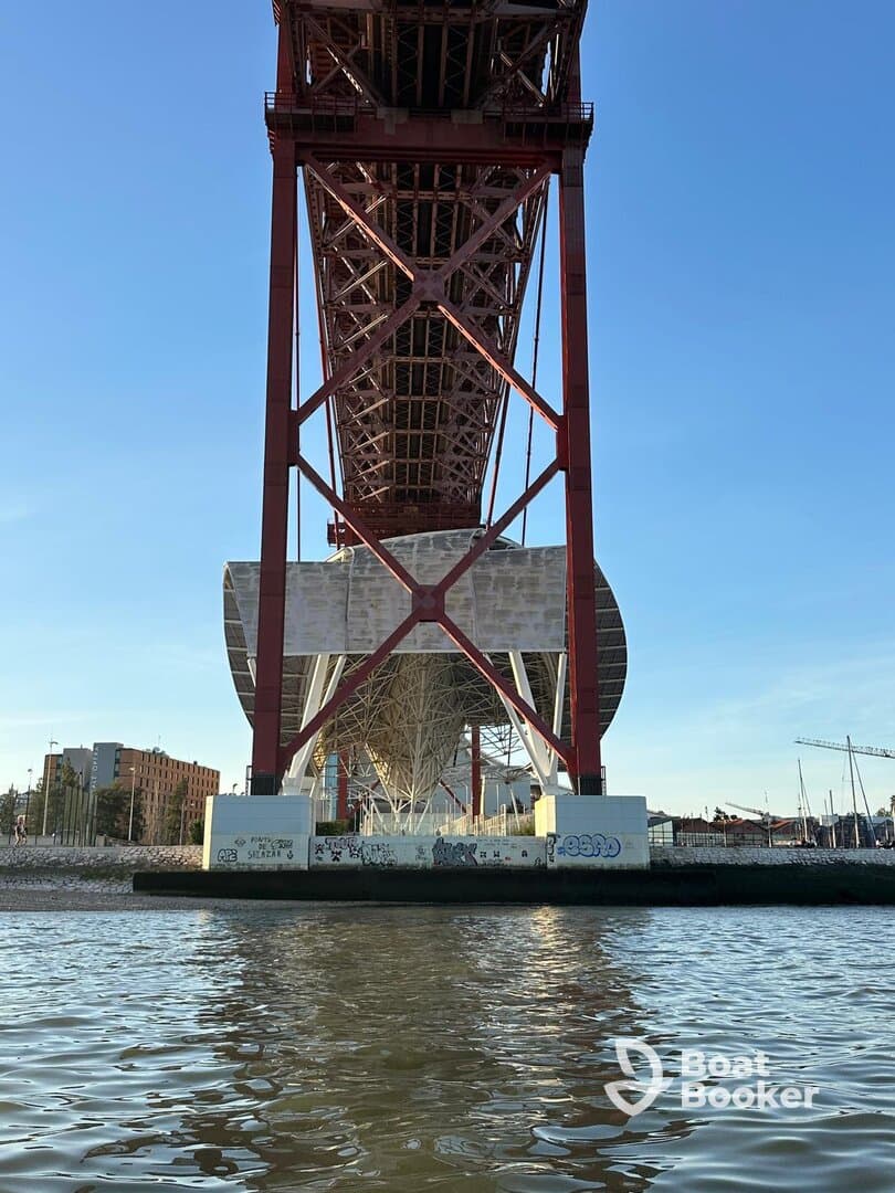 A view of a large structure from below, with water in the foreground. The image lacks clarity and focus.