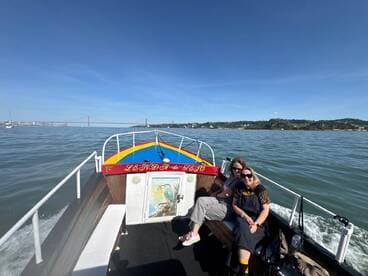 Two friends enjoy a sunny day on a boat in Lisbon, capturing the joy of their aquatic adventure against a scenic backdrop.