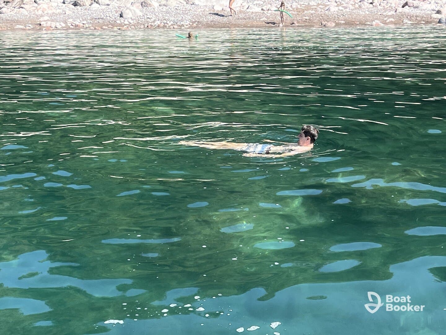 A person enjoys a refreshing swim in crystal-clear waters, surrounded by a beautiful beach setting — perfect for summer adventures.
