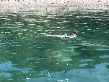 A person enjoys a refreshing swim in crystal-clear waters, surrounded by a beautiful beach setting — perfect for summer adventures.