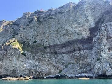 A stunning view of a rocky coastline, showcasing the natural beauty of the cliffs against the clear blue sky and tranquil waters — perfect for nature lovers and scenic boat tours.
