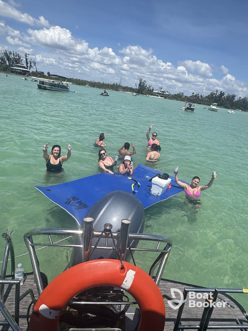 A lively group enjoys a fun day in the water, celebrating with drinks on a floating mat — the perfect backdrop for a summer party in the sun.