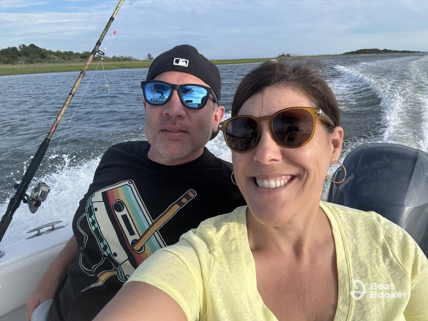 A cheerful couple enjoys a fishing trip on a boat, capturing a memorable moment with smiles and scenic views in the background.
