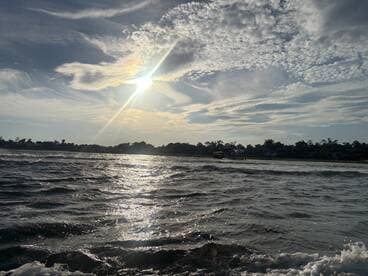 A scenic view of the water and sky, capturing the sun's rays, but lacks clarity and identifiable subjects.