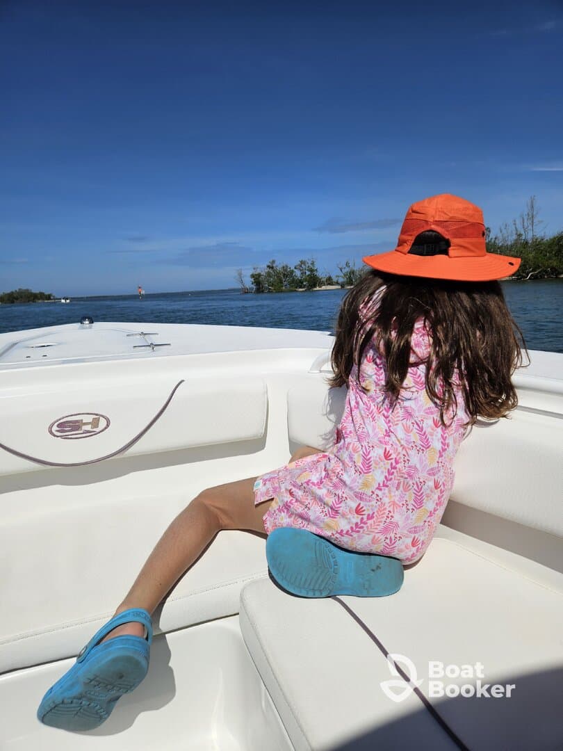 A young girl enjoys the view from the boat, soaking in the beautiful scenery and tranquil waters — a perfect moment for family outings on the water.