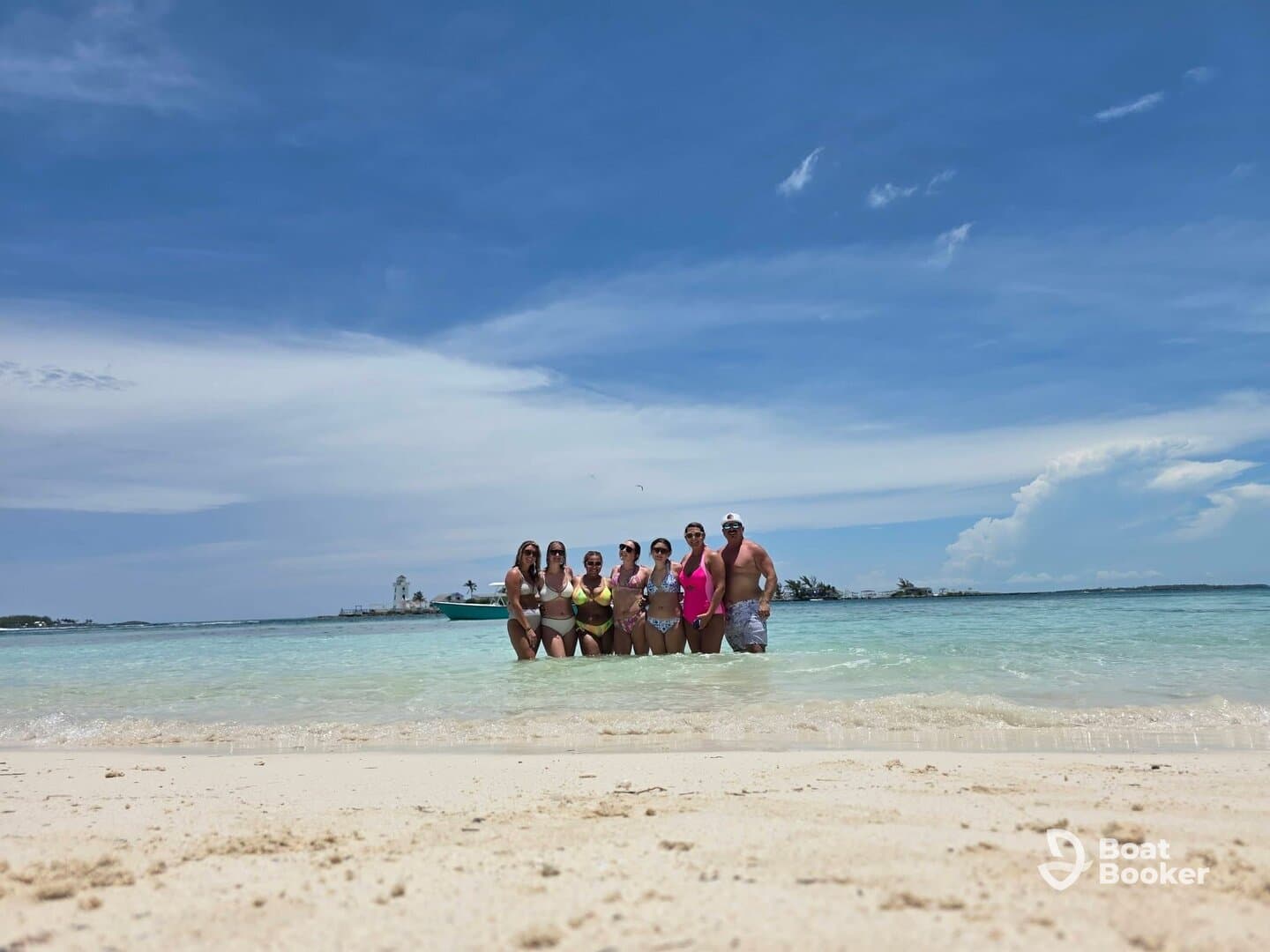 A lively group enjoys a sunny day at the beach, wading in the shallow waters and celebrating together — perfect for summer fun and memorable outings.