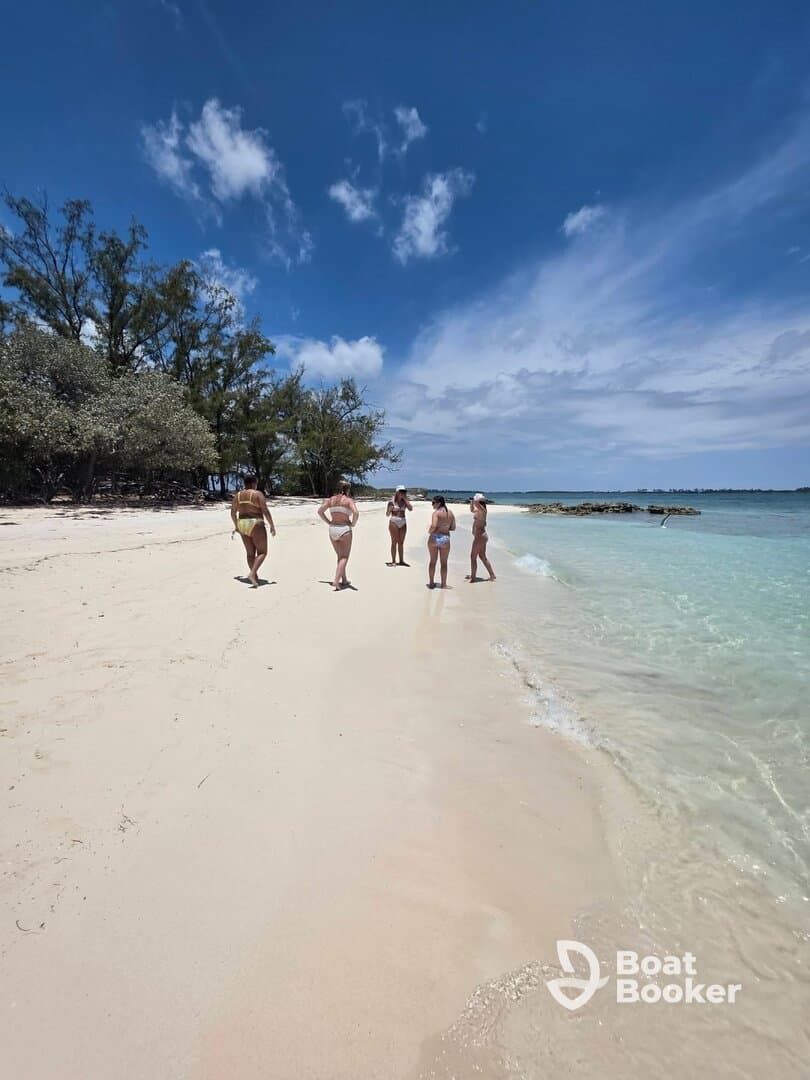 A group of friends strolls along a beautiful beach under a clear blue sky, enjoying a perfect day in the sun — ideal for beach vacations and group getaways.