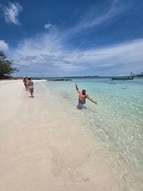 A group of friends enjoys a sunny day at the beach, with one person playfully splashing in the water — a perfect sandbar stop for fun and relaxation.