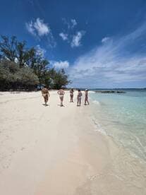 A group of friends strolls along a beautiful beach under a clear blue sky, enjoying a perfect day in the sun — ideal for beach vacations and group getaways.