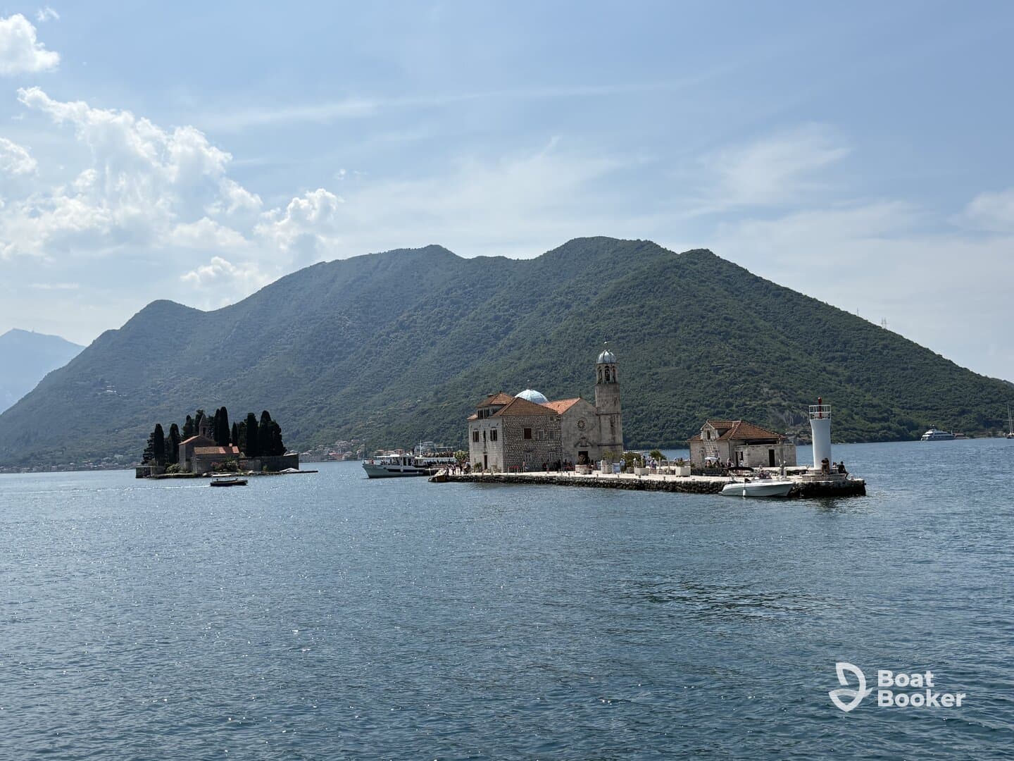 A picturesque view of an island with historic buildings set against a stunning mountainous backdrop, perfect for exploring coastal landmarks and enjoying scenic boat tours.