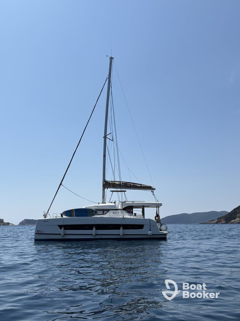 A stunning side view of a Bali catamaran sailing in calm waters, showcasing its sleek design against a clear blue sky.