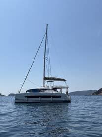 A stunning side view of a Bali catamaran sailing in calm waters, showcasing its sleek design against a clear blue sky.