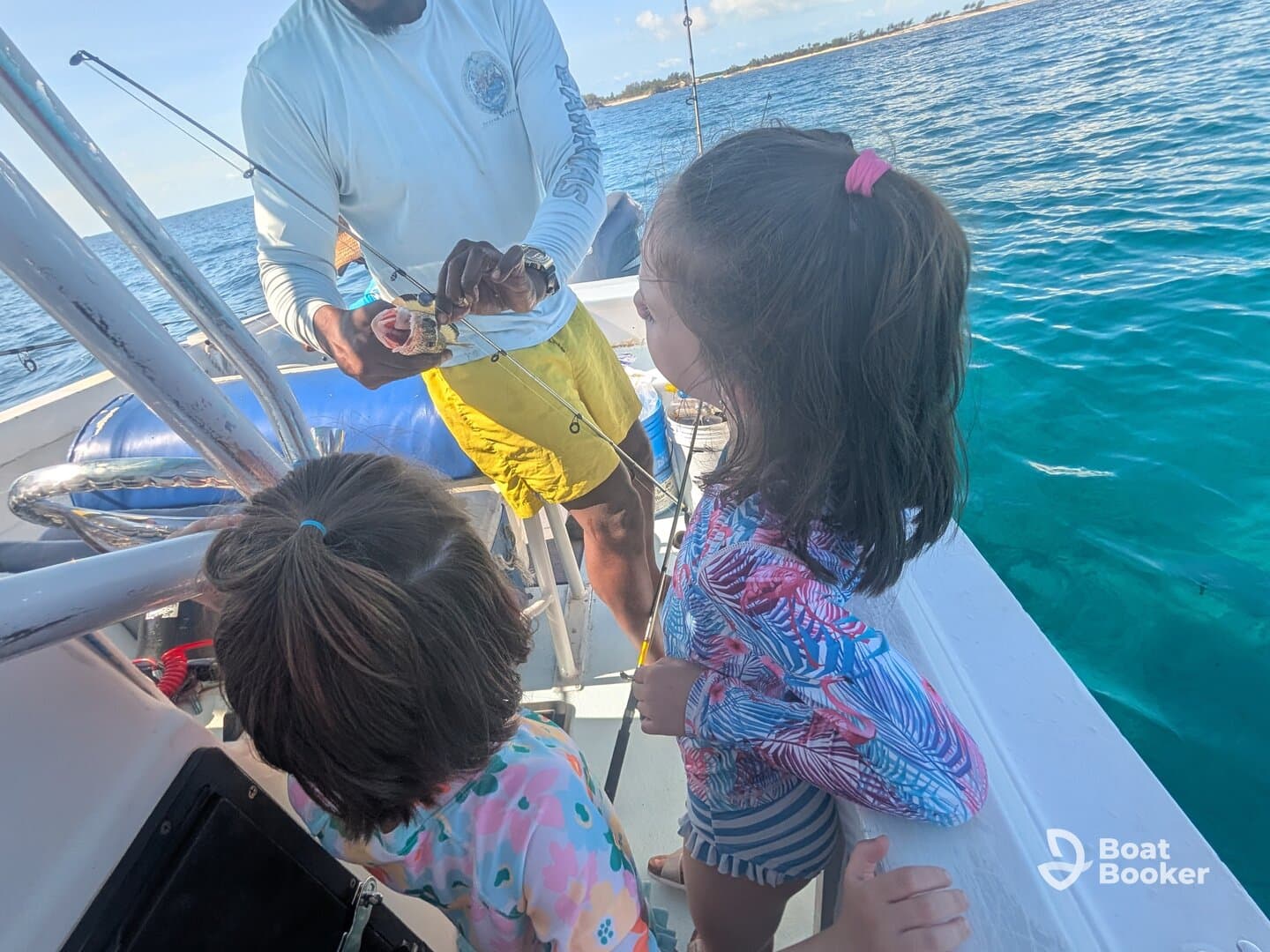 Two children watch in awe as an adult shows them a caught fish on a boat, creating a memorable fishing experience on the water.